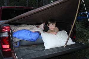 Young boy with a self-made fort in the back of a truck