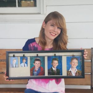 MaryJo holding a frame of her kids' many school picture day pictures