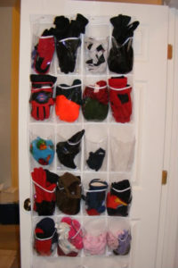 Plastic over the door organizer containing mittens, hats, and scarves